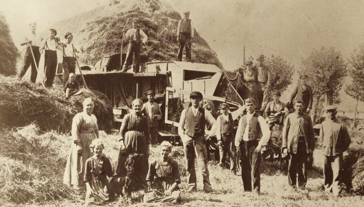 Landarbeiter vor einer Dreschmaschine auf einem Holsteinschen Gut um 1920